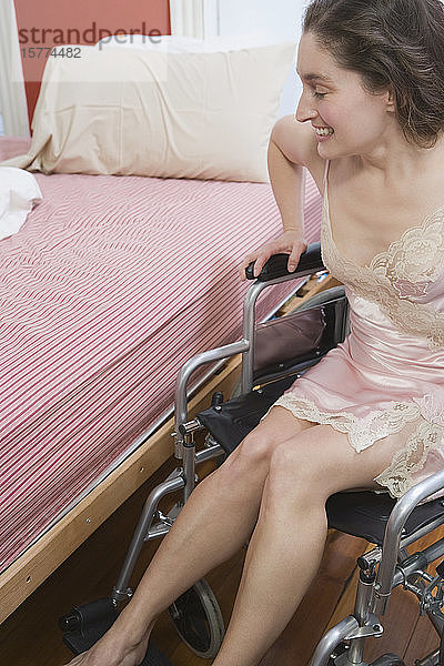 Mittlere erwachsene Frau sitzt im Rollstuhl und lächelt