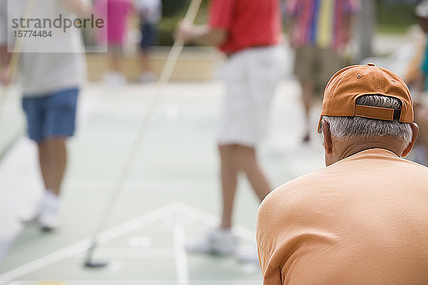 Rückansicht eines älteren Mannes beim Shuffleboard spielen