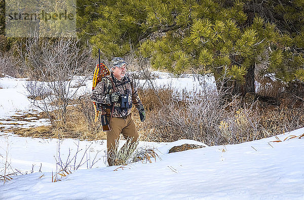 Jäger mit Schneeschuhen  Gewehr und Fernglas auf dem Weg in den Schnee; Denver  Colorado  Vereinigte Staaten von Amerika