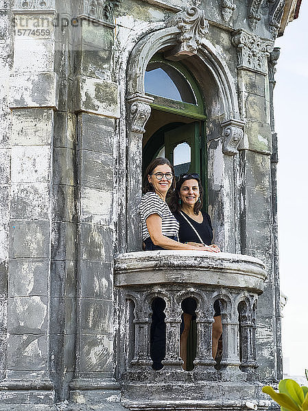 Zwei Frauen stehen auf dem Balkon eines alten Gebäudes und schauen in die Kamera; Havanna  Kuba