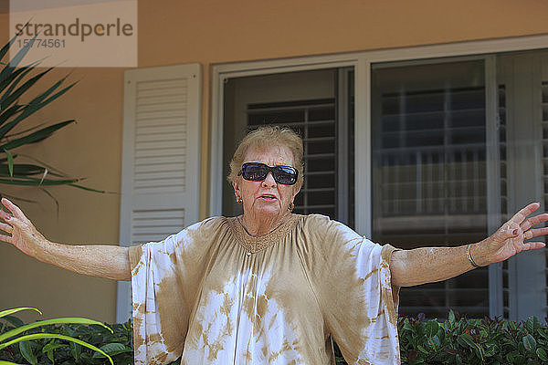 Ältere Frau schaut mit Sonnenbrille in die Kamera und spricht