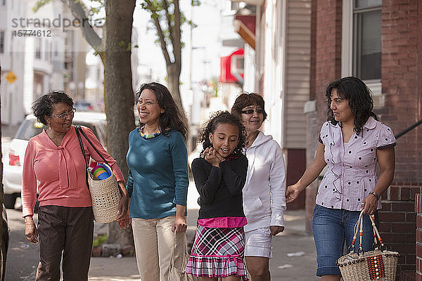 Frauen aus drei Generationen verbringen Zeit miteinander  indem sie einen Bürgersteig entlanggehen