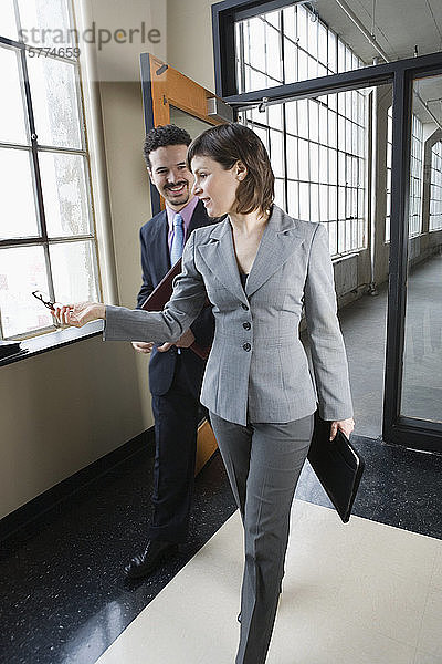 Eine Geschäftsfrau und ein Geschäftsmann gehen auf dem Flur eines Bürogebäudes