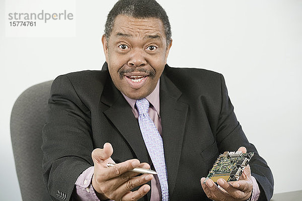 Porträt eines Geschäftsmannes  der einen Computerchip und einen Stift hält