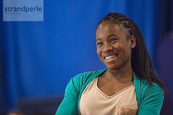 Eine junge afroamerikanische Frau sitzt mit einem Lächeln