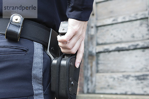 Nahaufnahme einer weiblichen Polizistin  die eine Pistole aus dem Holster zieht.