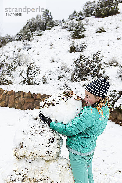 Ein junges Mädchen baut einen Schneemann