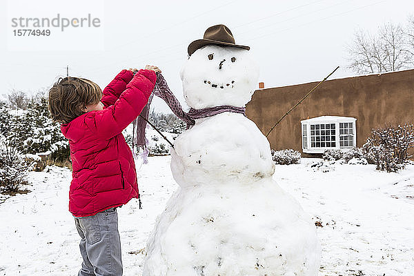 Ein kleiner Junge baut einen Schneemann