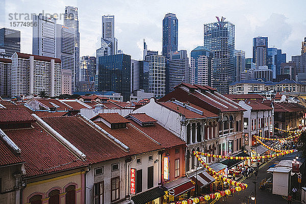 Schrägansicht auf die alten Geschäftshäuser von Chinatown und die modernen Wolkenkratzer von Singapur in der Abenddämmerung.