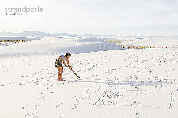 Ein junges Mädchen  das in den Sand zeichnet