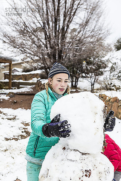 Ein junges Mädchen baut einen Schneemann