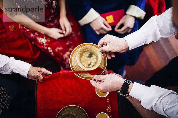 Nahaufnahme eines Rituals bei einer chinesischen Hochzeitszeremonie  bei der Menschen eine Schüssel Suppe reichen.