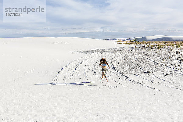 Ein jugendliches Mädchen rennt im Sand