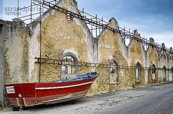 Rotes Boot liegt auf einer von baufälligen Gebäuden gesäumten Straße  Lissabon  Portugal.