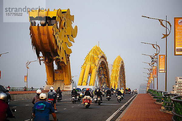 Rückansicht von Pendlern auf Motorrädern  die die Brücke in Form eines Drachens überqueren.