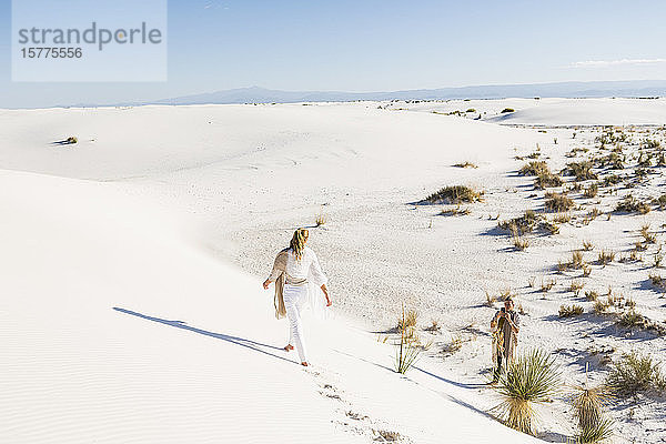 Ein Teenager-Mädchen geht über Sanddünen und hinterlässt Fußspuren