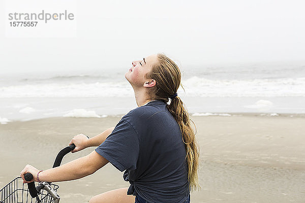 Ein Teenager radelt auf Sand am Strand