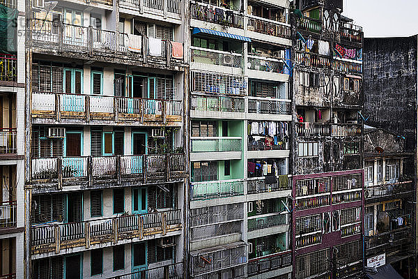 Fassade von Reihen heruntergekommener Mehrfamilienhäuser mit auf Balkonen hängender Wäsche.