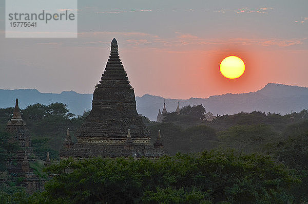 Sonnenuntergang über fernen Bergen mit Stupa des Tempels im Vordergrund  Bagan  Myanmar.