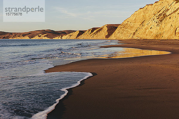 Strand in der Morgendämmerung  mit steilen Klippen und Felsen.