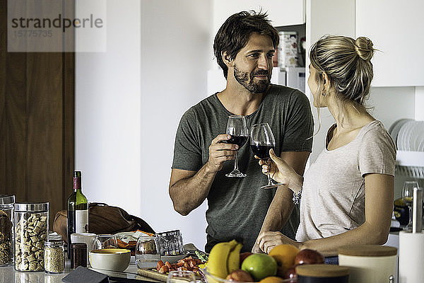 Ehepaar stößt in der Küche mit Weingläsern an