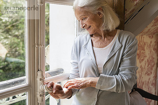 Ältere Frau steht am Fenster