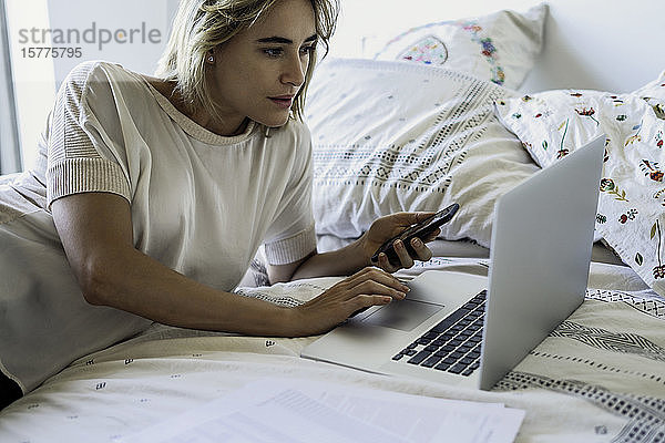 Frau mit Laptop auf dem Bett