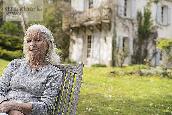 Ältere Frau sitzt im Garten