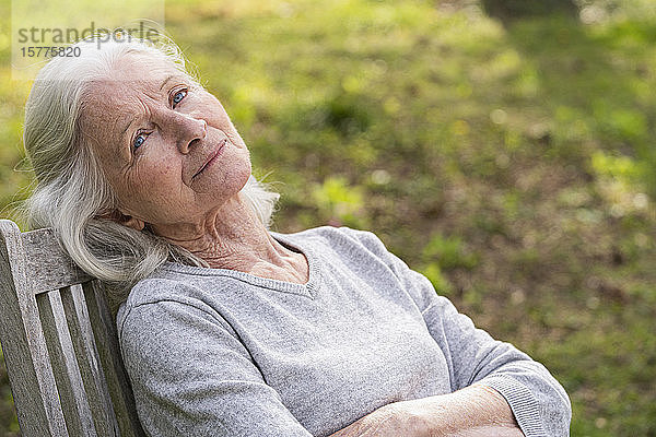 Nachdenkliche ältere Frau entspannt sich im Garten