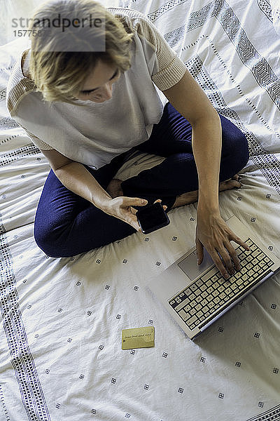 Frau mit Laptop auf dem Bett