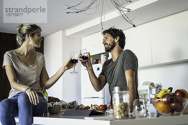 Ehepaar stößt in der Küche mit Weingläsern an