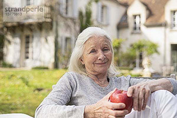 Porträt einer lächelnden älteren Frau  die im Garten sitzt