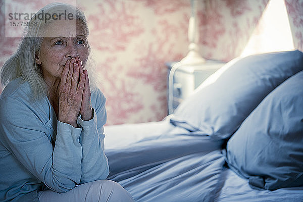 Ältere Frau auf dem Bett sitzend