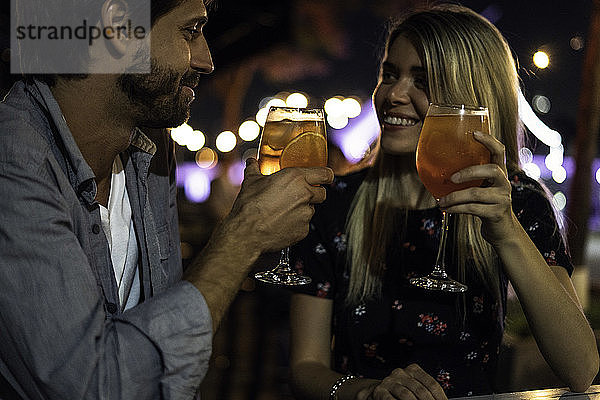 Junges Paar mit Cocktailgläsern in einem Straßencafé