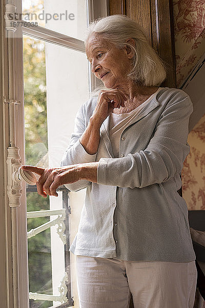Ältere Frau steht am Fenster