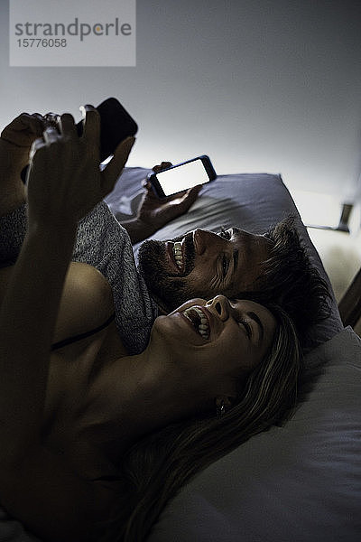 Fröhliches junges Paar mit Smartphones