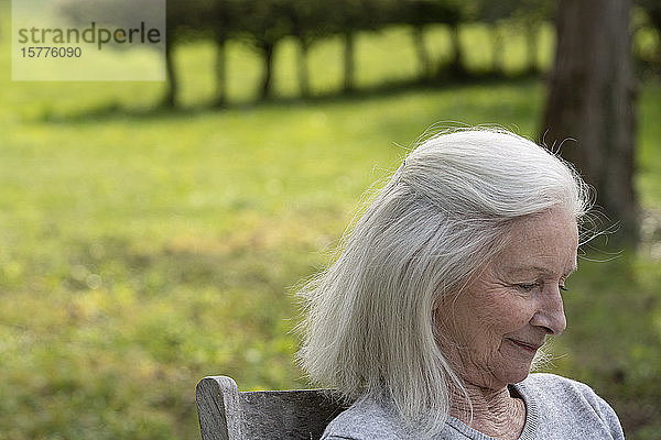 Ältere Frau sitzt im Garten