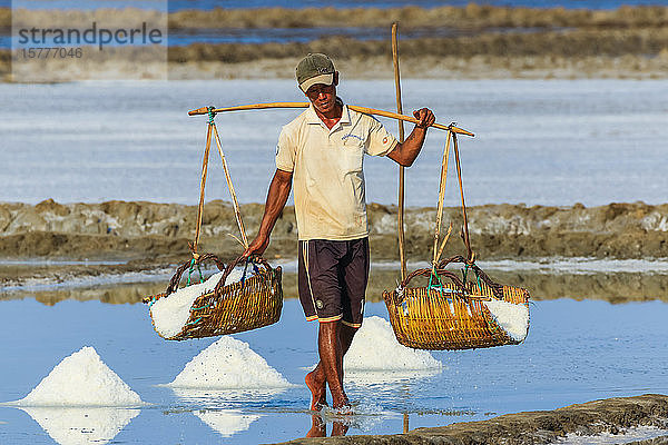 Mann mit Schulterstange bei der Ernte auf den Salzfeldern im Mündungsgebiet des Praek Tuek Chhu Flusses südlich der Stadt  Kampot  Kambodscha  Indochina  Südostasien  Asien