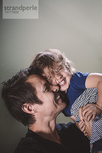 Porträt einer glücklichen Tochter mit lächelndem Vater an der Wand
