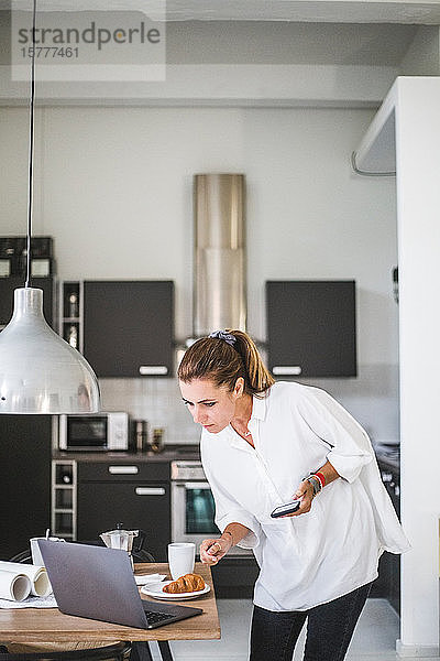 Unternehmerin arbeitet  während sie zu Hause auf den Laptop schaut