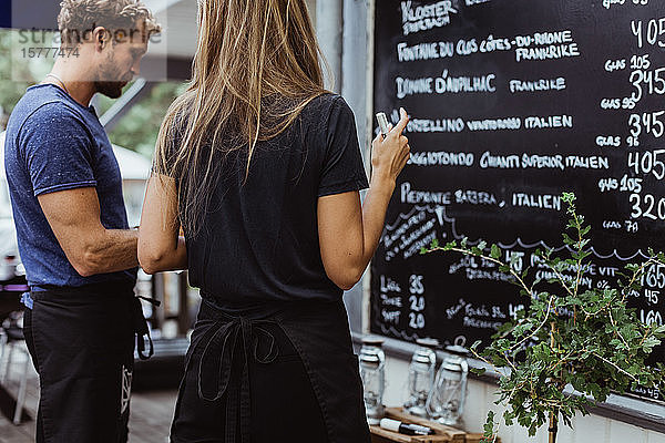 Rückansicht einer Geschäftsfrau  die mit einem Mitarbeiter im Restaurant an der Wand steht