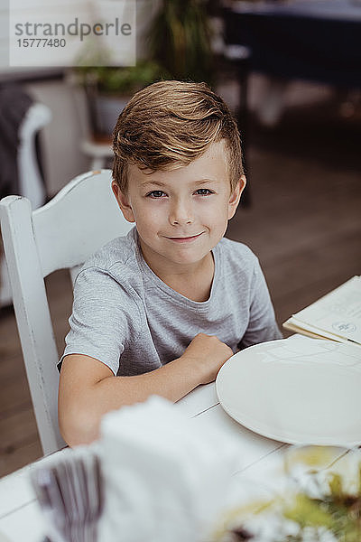 Porträt eines lächelnden Jungen  der am Tisch im Restaurant sitzt