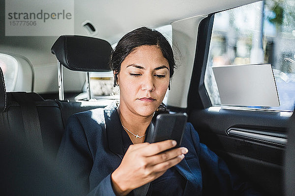 Geschäftsfrau benutzt Smartphone auf Reisen im Auto