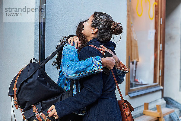 Lächelndes lesbisches Paar umarmt sich im Urlaub in der Stadt