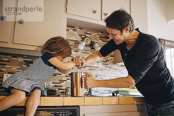 Reifer Vater und Tochter kochen zu Hause Kaffee in französischer Presse