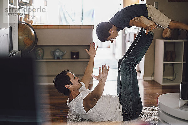Glücklicher Vater spielt  während er seinen Sohn in der Luft auf den Beinen hält