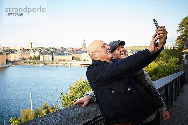 Lächelnde Freunde nehmen Selfie mit Handy gegen Fluss in der Stadt