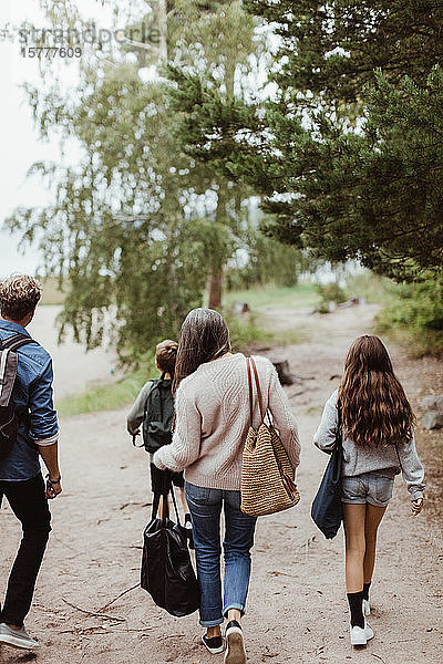 Familie in voller Länge mit Taschen auf Fußweg inmitten eines Baumes im Wald
