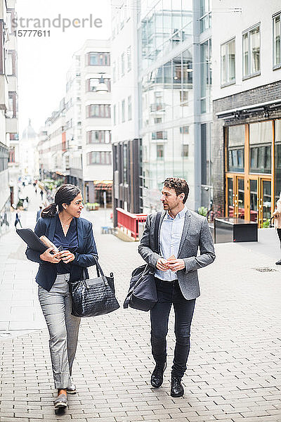 Männliche und weibliche Geschäftsleute unterhalten sich beim Spaziergang in der Stadt