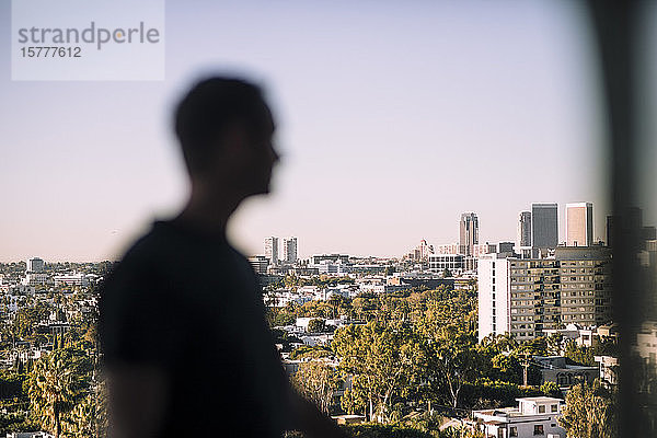 Seitenansicht eines reifen Mannes  der auf einem Balkon gegen die Stadt steht